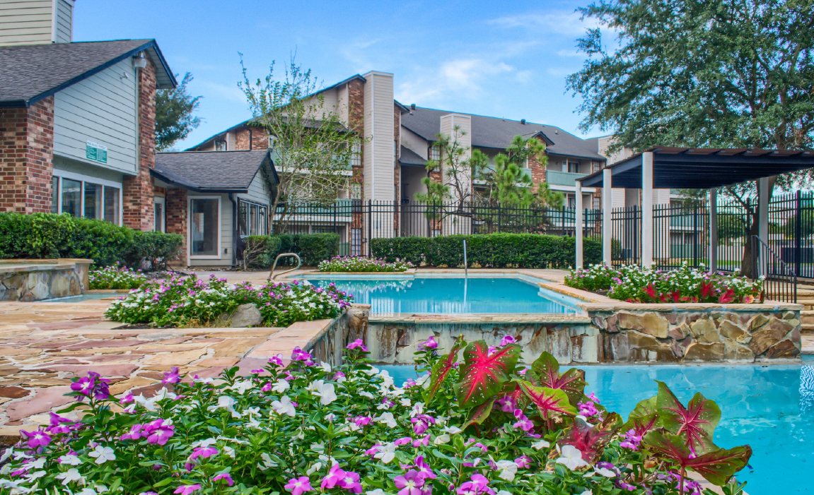 Resort-style pool area with gardens Chateau Carmel New Orleans apartments
