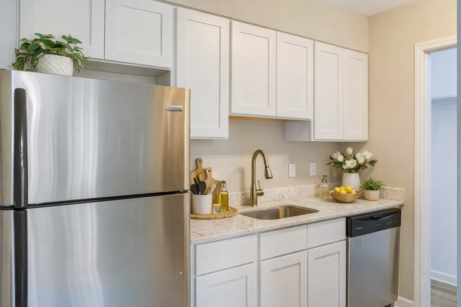 Kitchen with white cabinets, stainless steel refrigerator, and gold fixtures at Chateau Carmel in New Orleans, LA